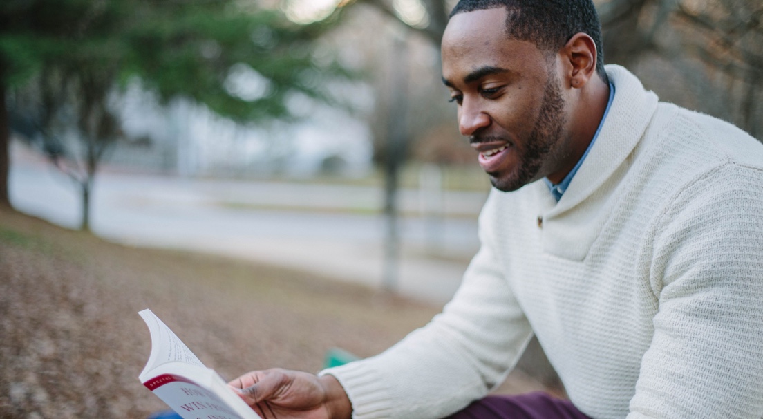 A college student outside reading.